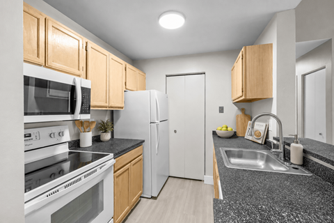A kitchen with a white refrigerator, white oven, and wooden cabinets.