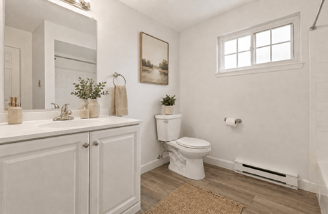 A white bathroom with a toilet, sink, and a window.