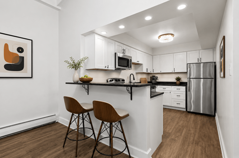 A kitchen with white cabinets and a black countertop.
