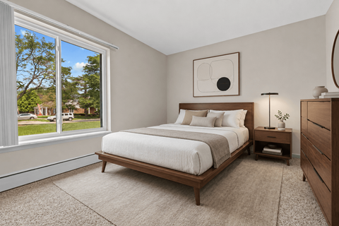 A bedroom with a large bed and a window overlooking a green area.