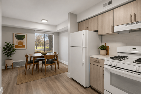 A kitchen with a white refrigerator, a dining table with chairs, and a stove top oven.