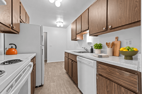 A kitchen with white appliances and wooden cabinets.