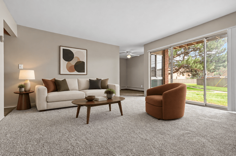 A living room with a white couch, a brown chair, and a painting on the wall.