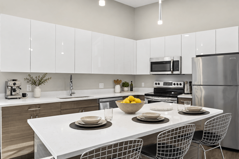 A modern kitchen with a white table and chairs set for a meal.
