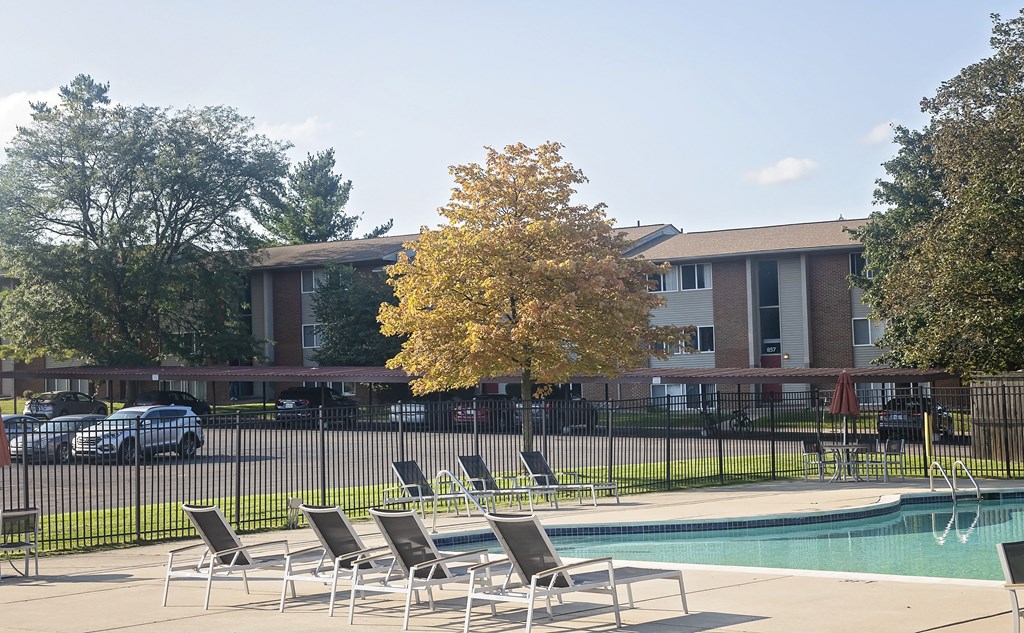a pool with chairs and a building in the background