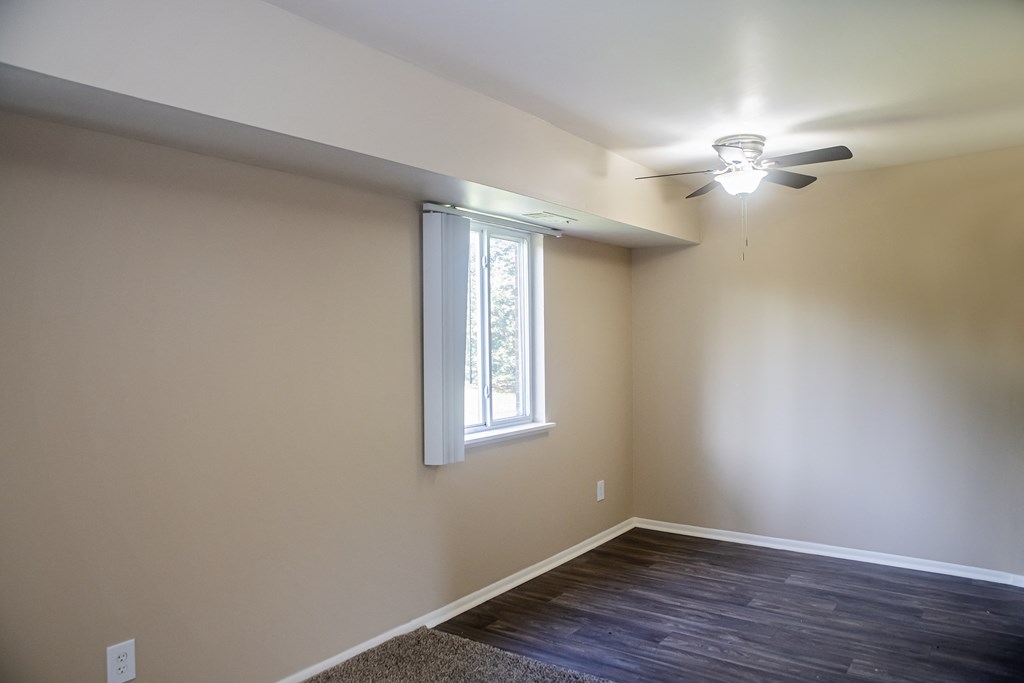 an empty room with a ceiling fan and a window