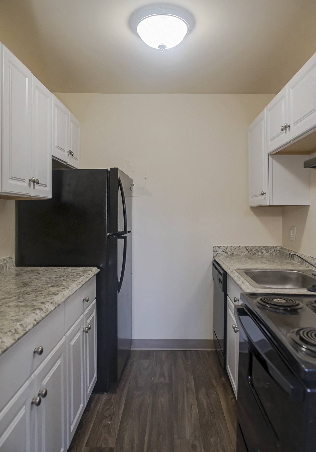 an empty kitchen with white cabinets and a black refrigerator and stove