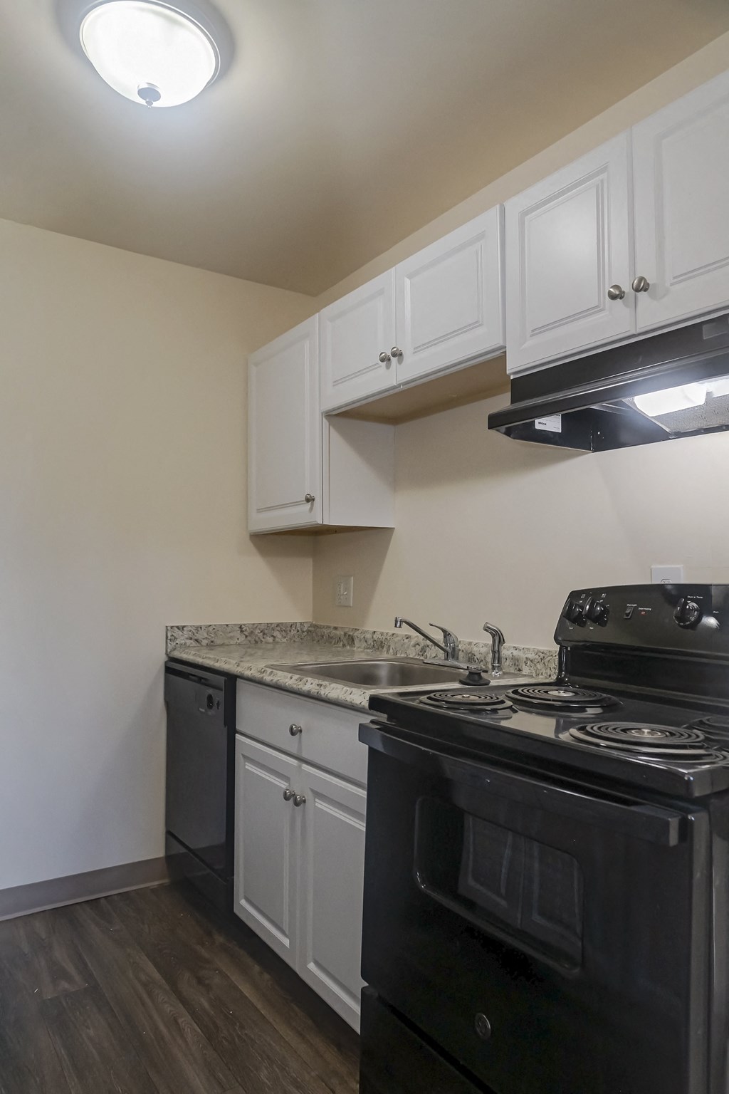 an empty kitchen with white cabinets and a black stove and oven