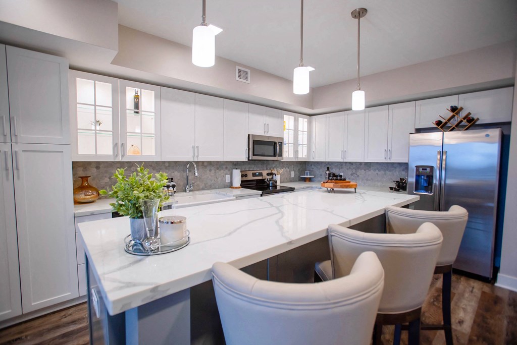 a large kitchen with white cabinets and a marble counter top
