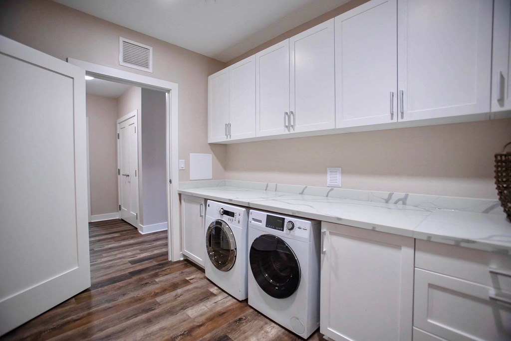 a washer and dryer in a laundry room with white cabinets