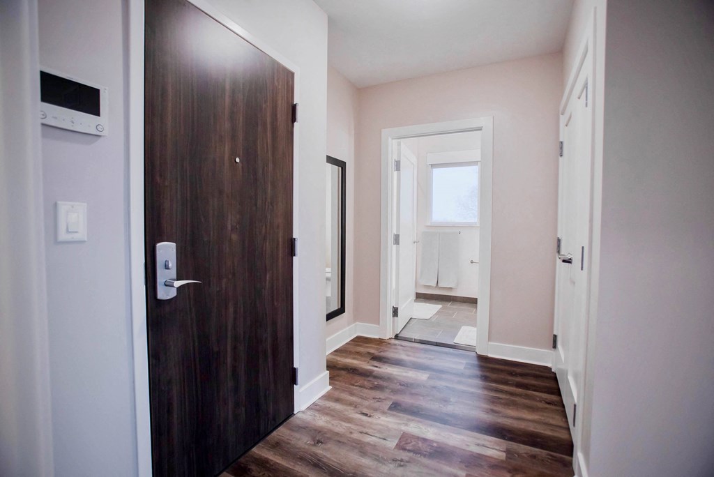a wooden door leading into a room with wood floors and white walls
