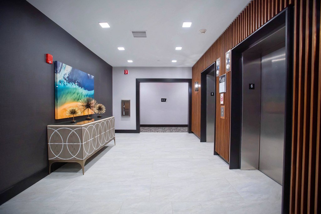 a hallway with elevators and a table with a painting