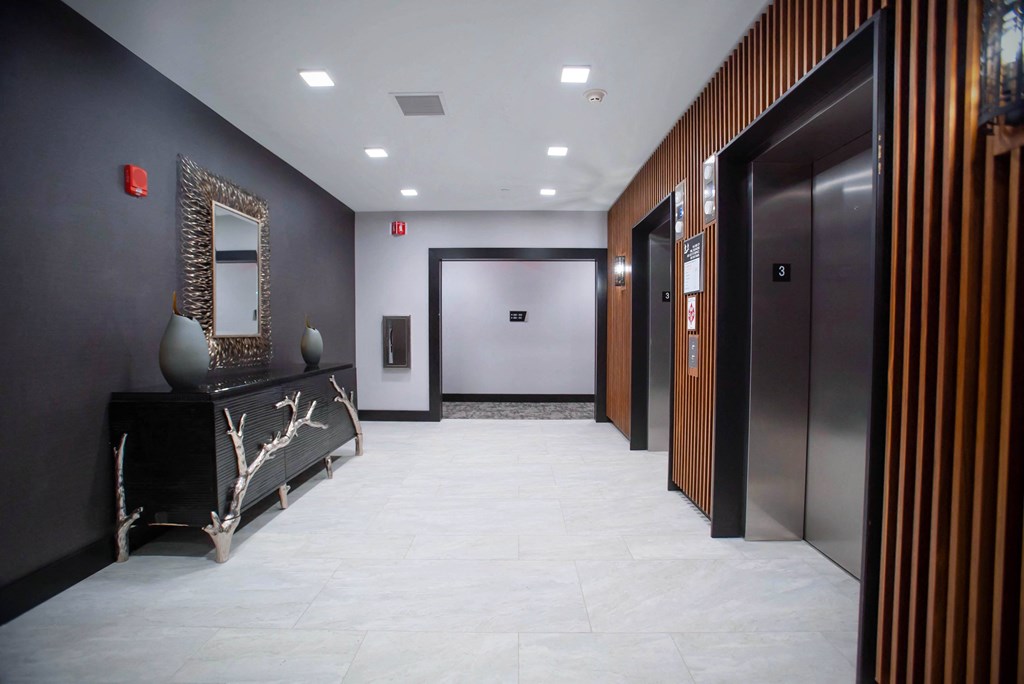 a hallway with elevators and a dresser and a mirror in a hotel lobby