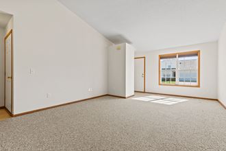 a spacious living room with carpet and a window