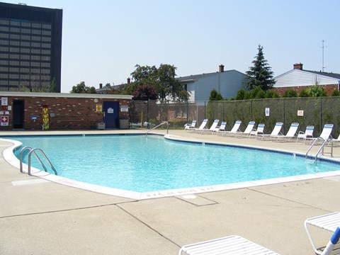 a swimming pool with white chairs and a building in the background