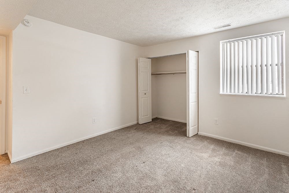 an empty bedroom with a closet and a window