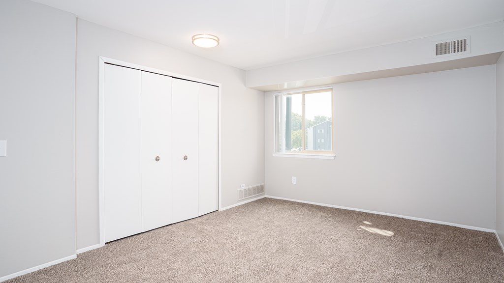 A room with a white door and carpeted floor.