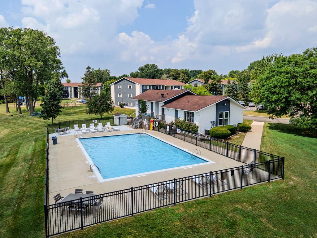A pool surrounded by a black fence with a house in the background.