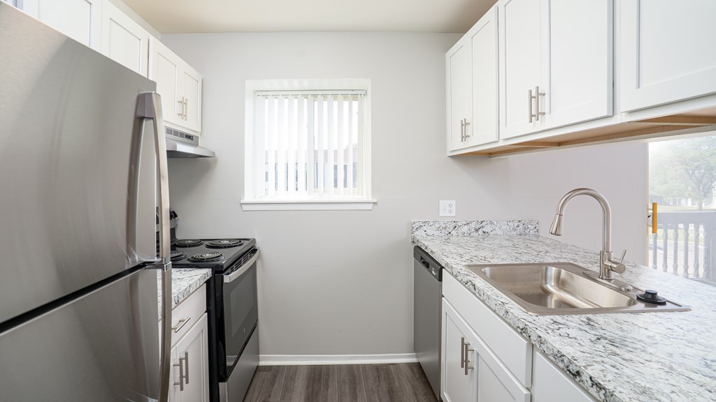 A kitchen with a stainless steel refrigerator and white cabinets.