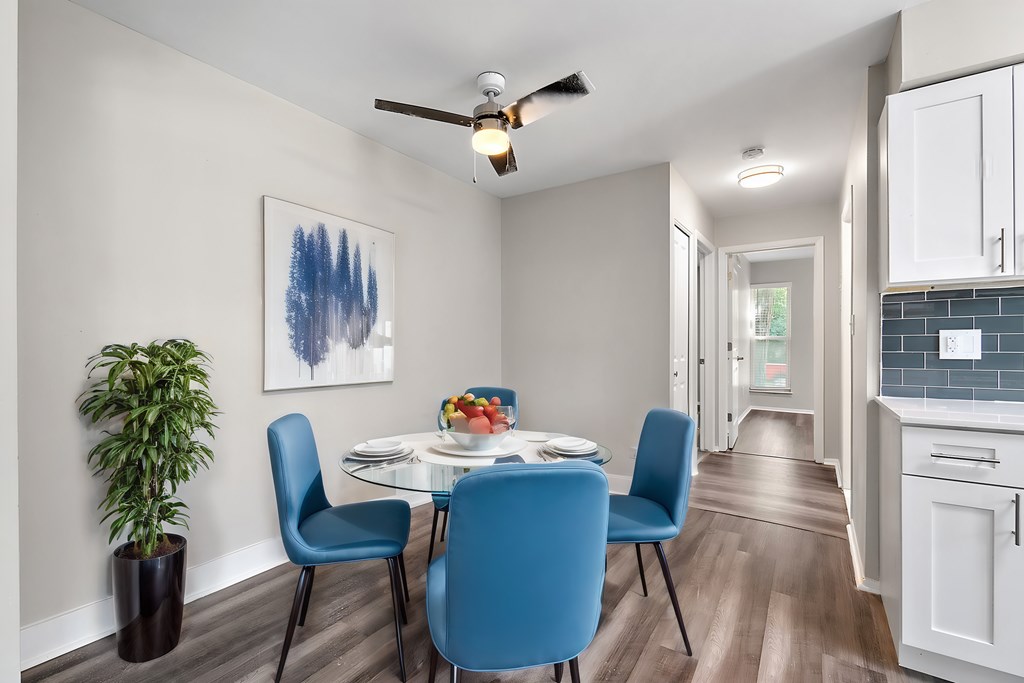 A dining room with a table set for two and a potted plant.