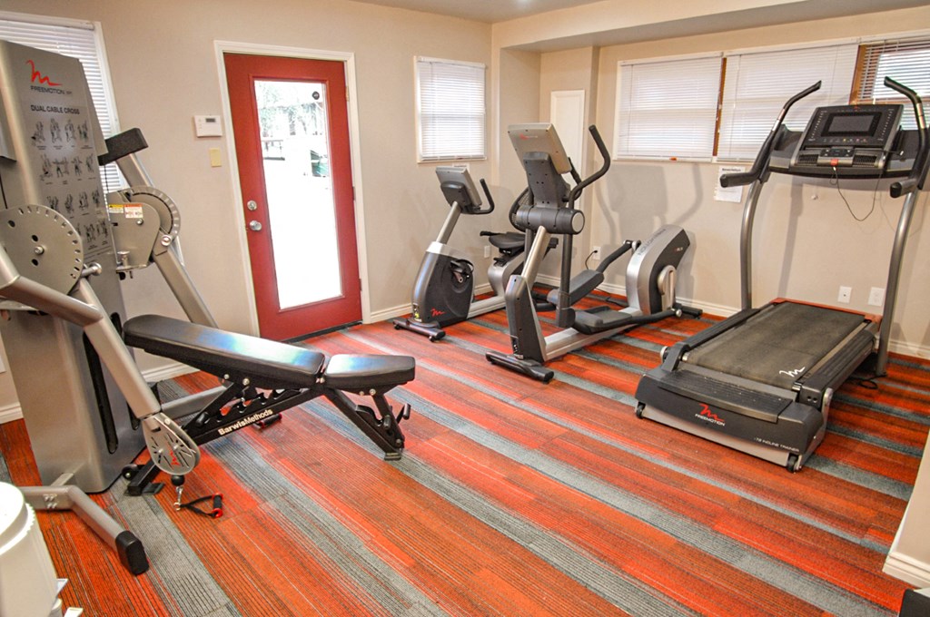 a gym with various exercise equipment on the floor and a door