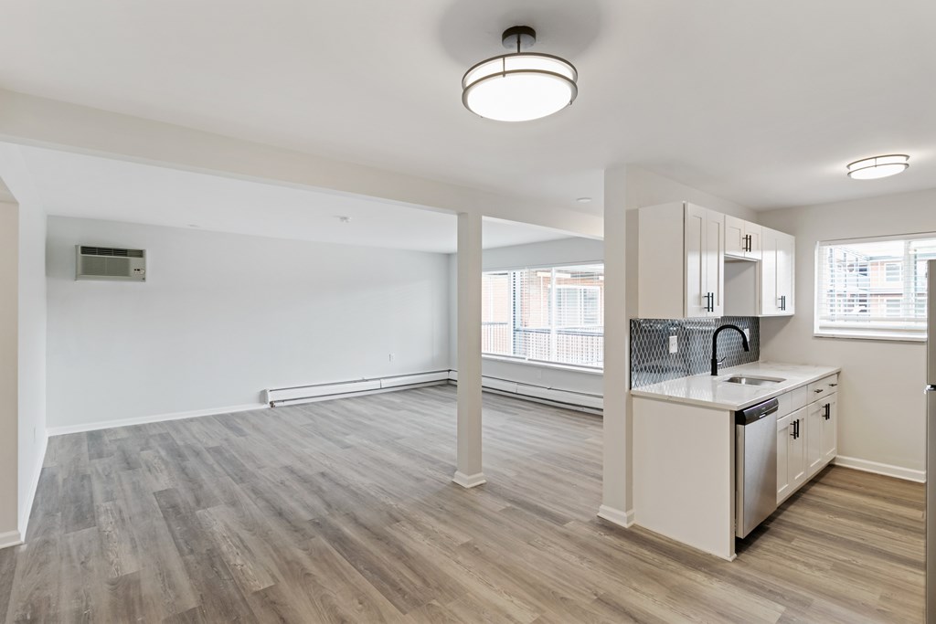 A kitchen area with a sink, stove, and cabinets.