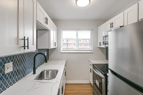 A kitchen with white cabinets and a blue tile backsplash.