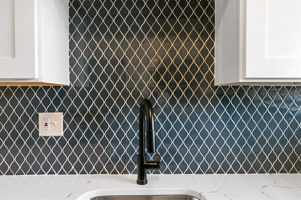 A kitchen sink with a black faucet and a tile backsplash.