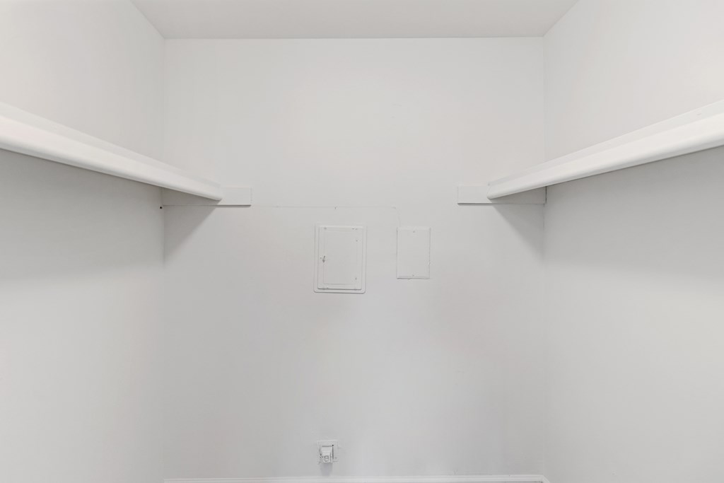 A white pantry with two shelves and a door.