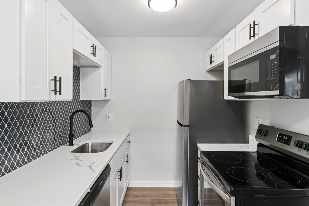 A kitchen with black and white appliances and cabinets.