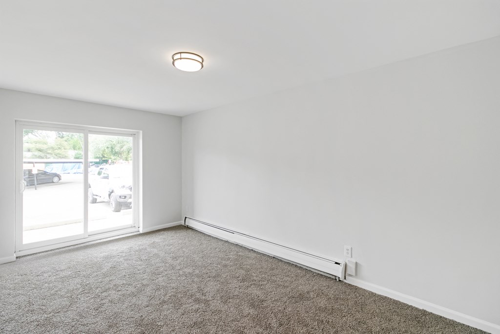 A room with a carpeted floor and a window.