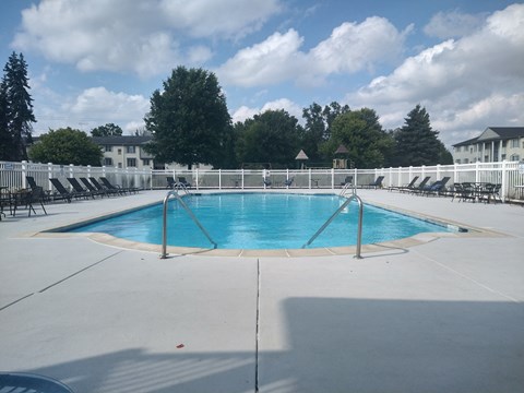 a swimming pool with chairs and a fence around it