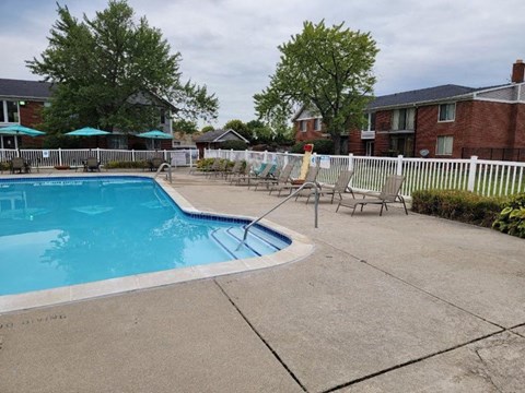 A small pool surrounded by a white fence and a white bench.