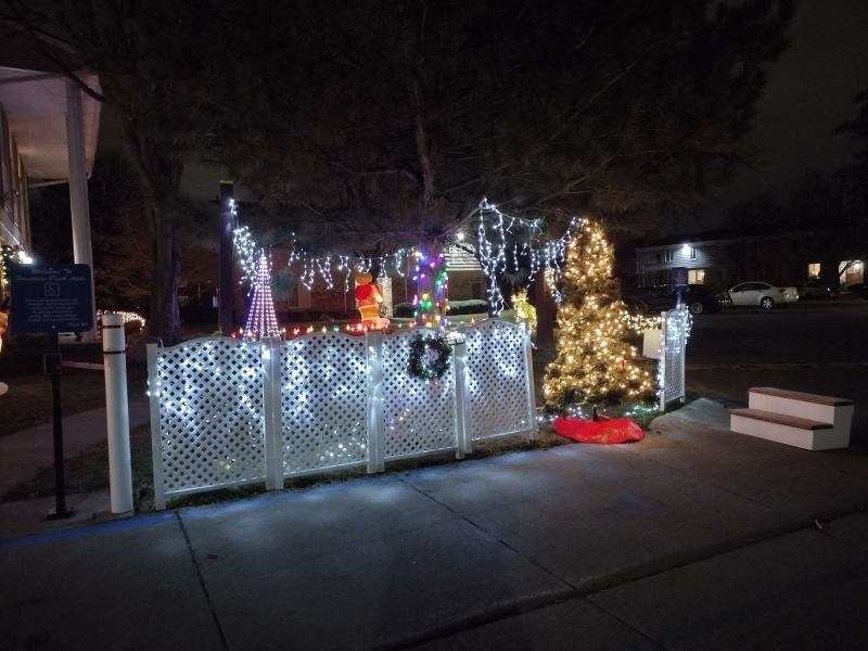 a fence covered in christmas lights and a christmas tree