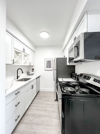 a kitchen with white cabinetry and black appliances  at Park On Canal Apartments, Clinton Twp, MI, 48038