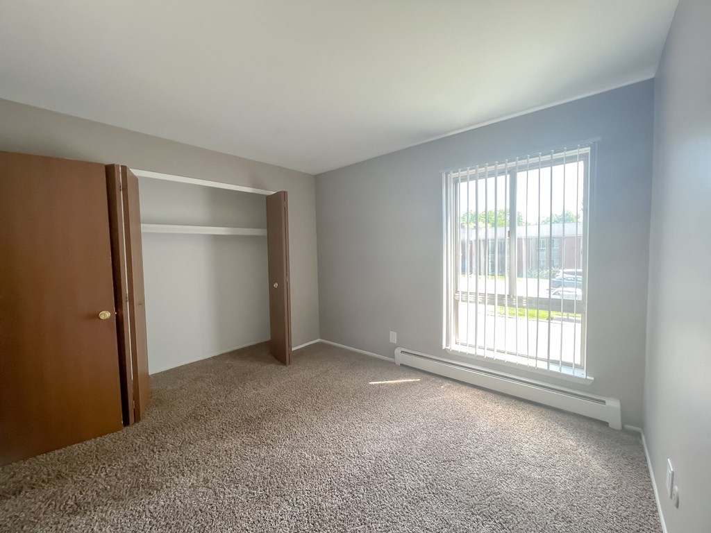 an empty bedroom with a large window and a closet