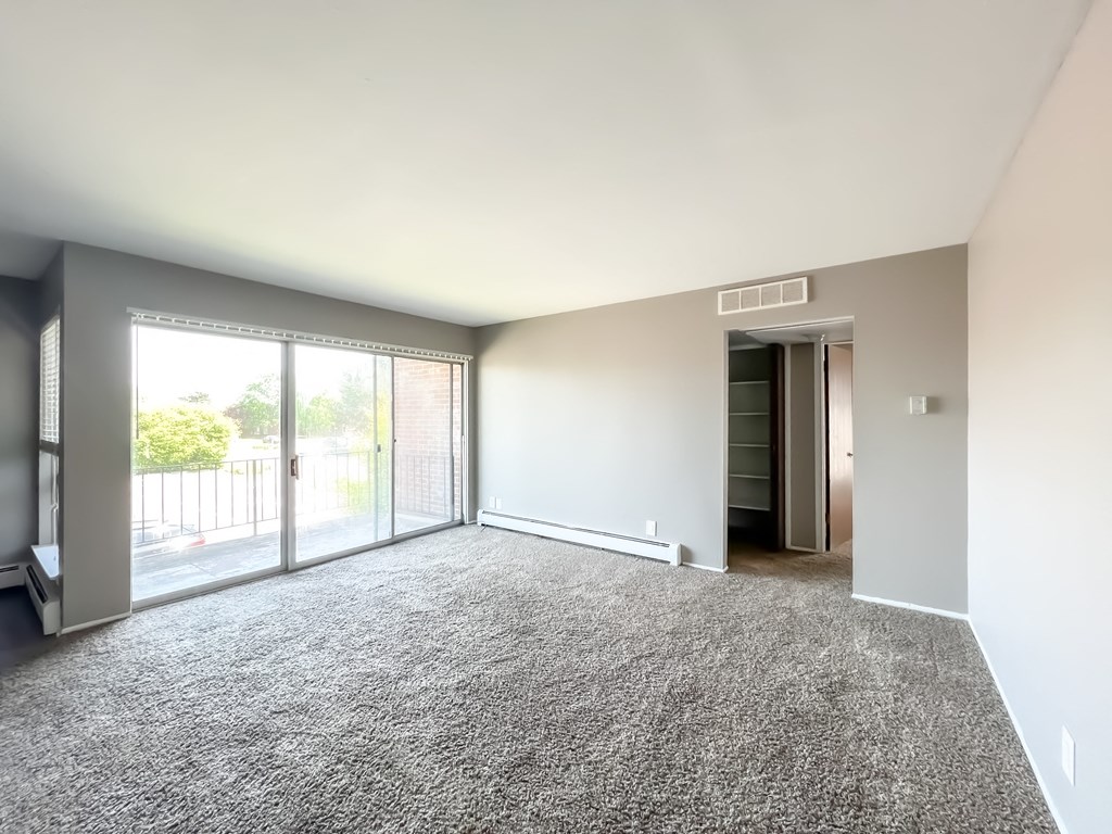 an empty living room with a sliding glass door and a balcony
