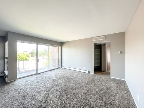 an empty living room with a sliding glass door and a balcony