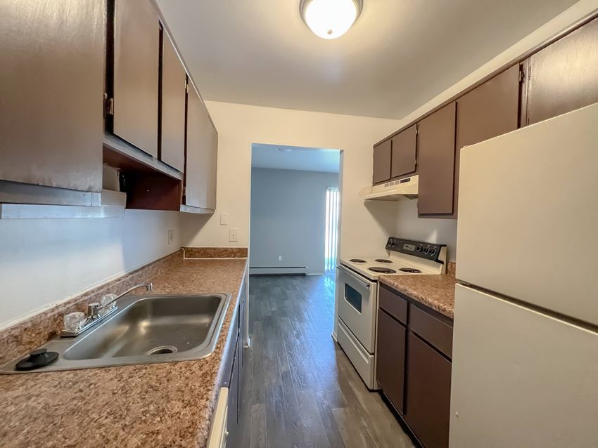 a kitchen with brown cabinets and a white stove top oven - Photo Gallery