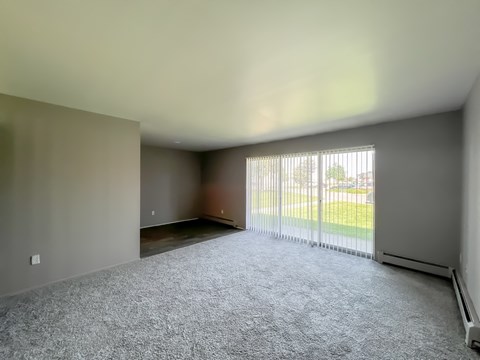 an empty living room with a large window and a white carpet