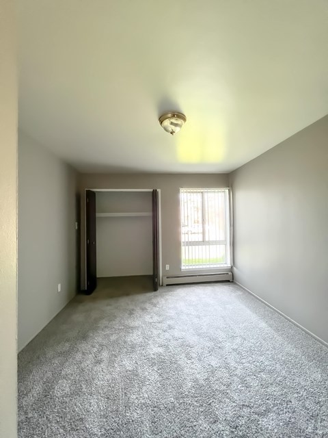 an empty bedroom with a window and a closet