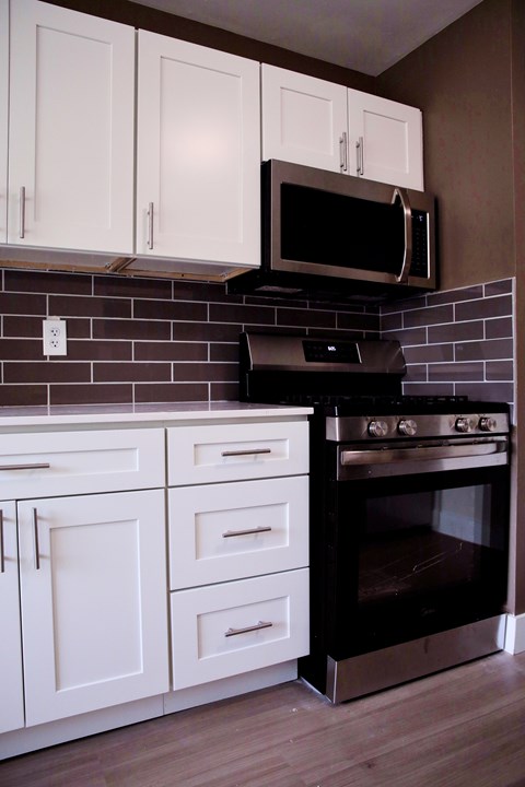 A black oven and microwave in a kitchen with white cabinets.