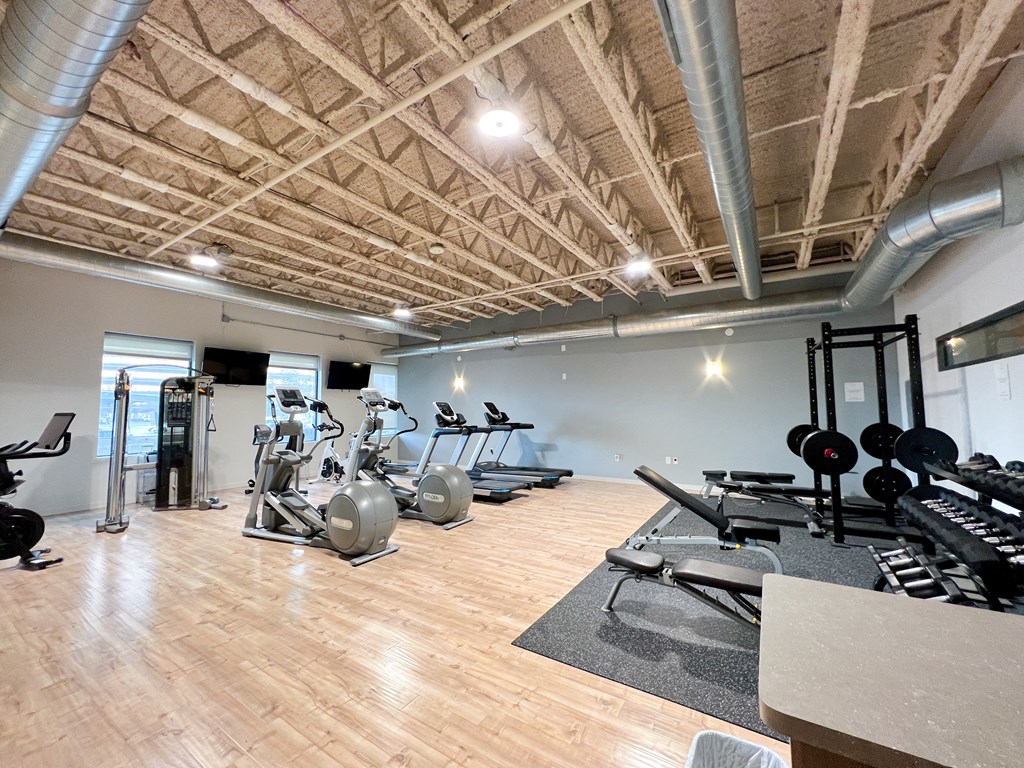 a spacious fitness room with cardio machines and weights