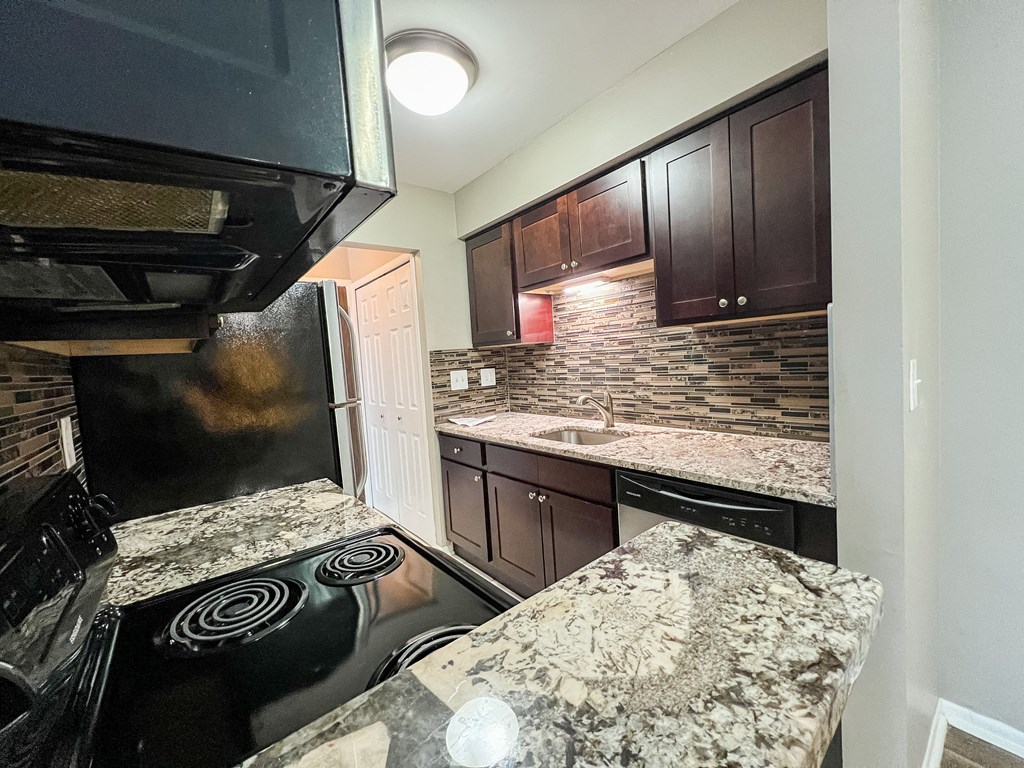 a kitchen with granite countertops and black appliances at Apple Ridge Apartments - Livonia, MI, Livonia, MI, 48152