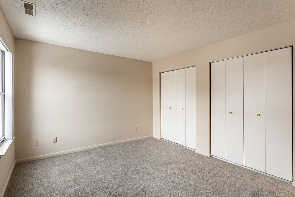 an empty bedroom with white closet doors