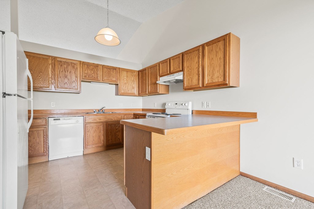 an empty kitchen with wooden cabinets and a counter top