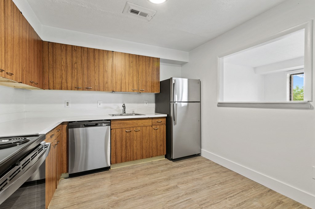 a kitchen with wooden cabinets and stainless steel appliances and a window