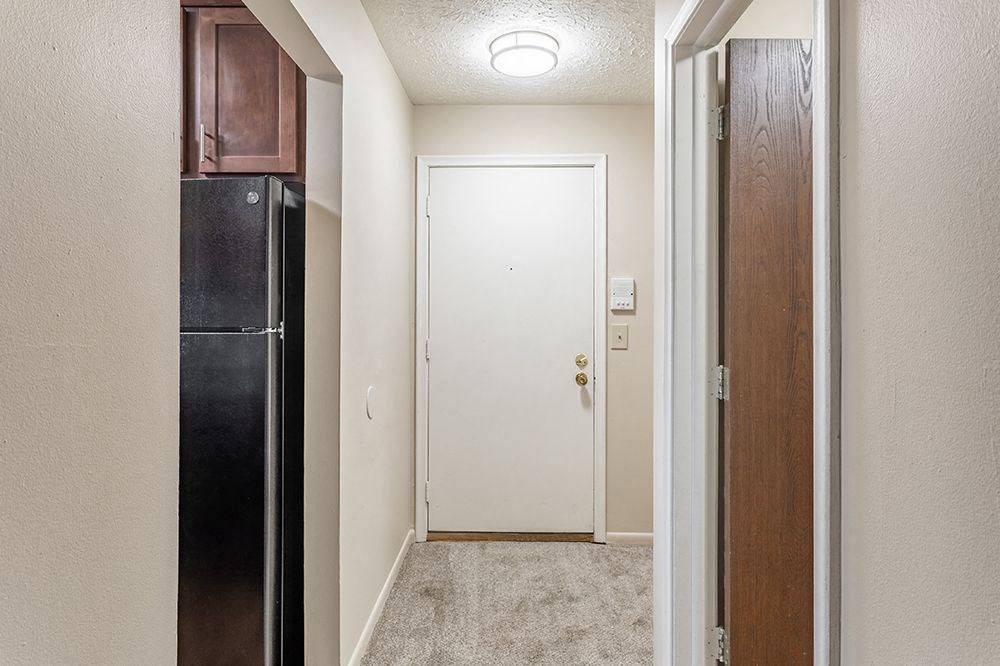 a hallway with a black refrigerator and a white door