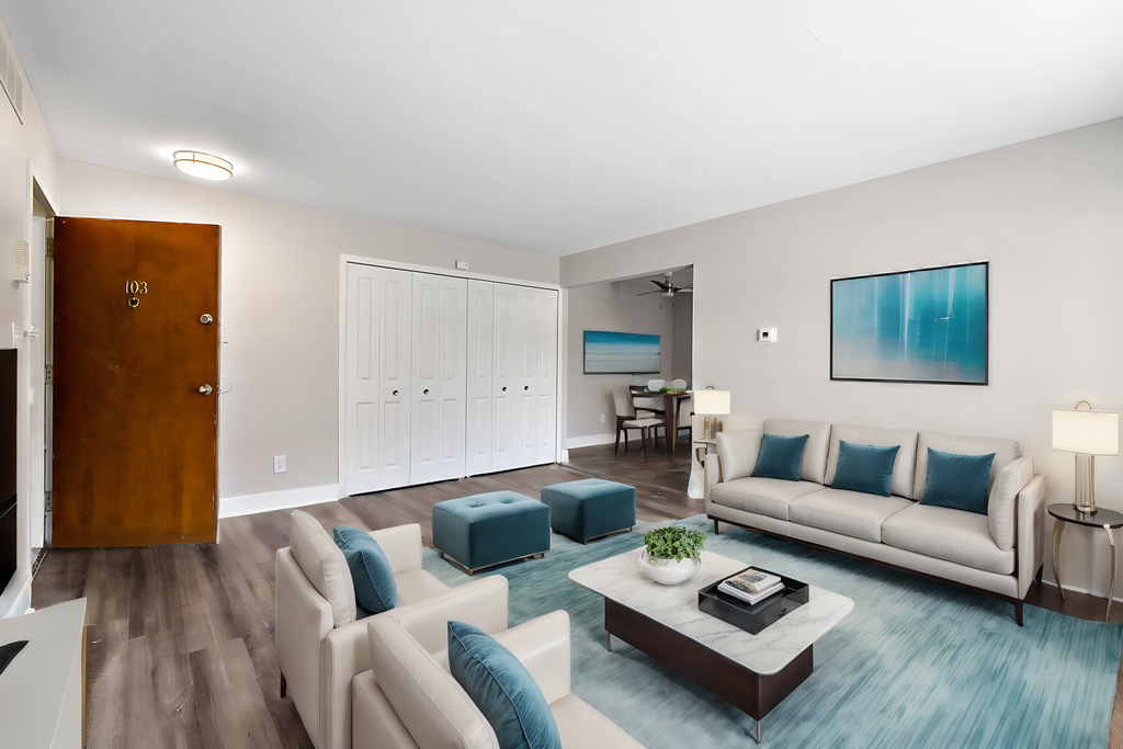 A living room with a white couch and a blue ottoman.