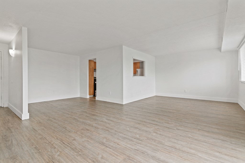 an empty living room with wood floors and white walls
